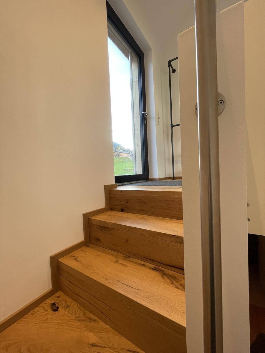 Helle Holztreppe führt zu einem oberen Bereich mit viel Tageslicht durch die Tür.