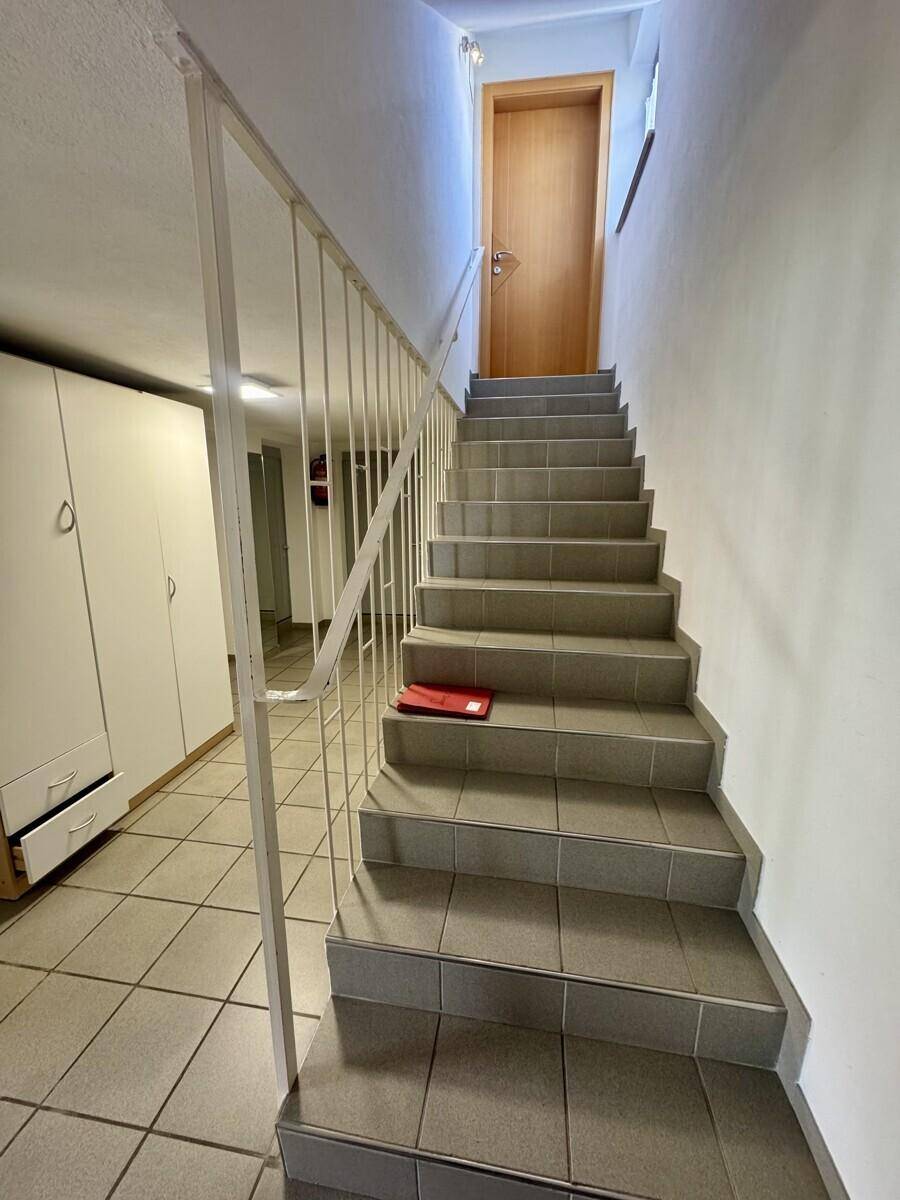 Treppenhaus mit gefliestem Boden und Geländer, das zu den oberen Etagen führt.