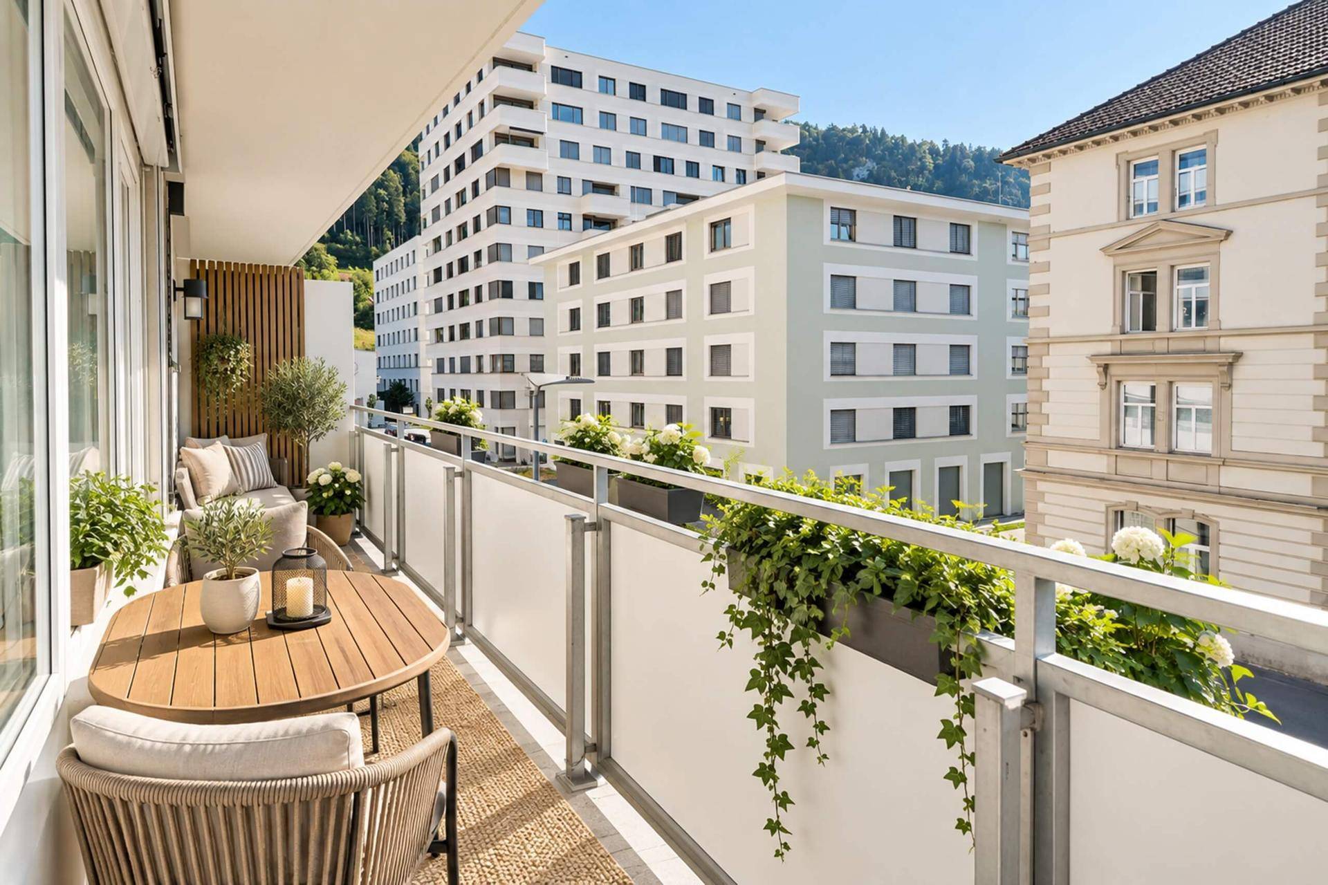 Möblierter Balkon mit Pflanzen und Blick auf umliegende Gebäude und Berge.