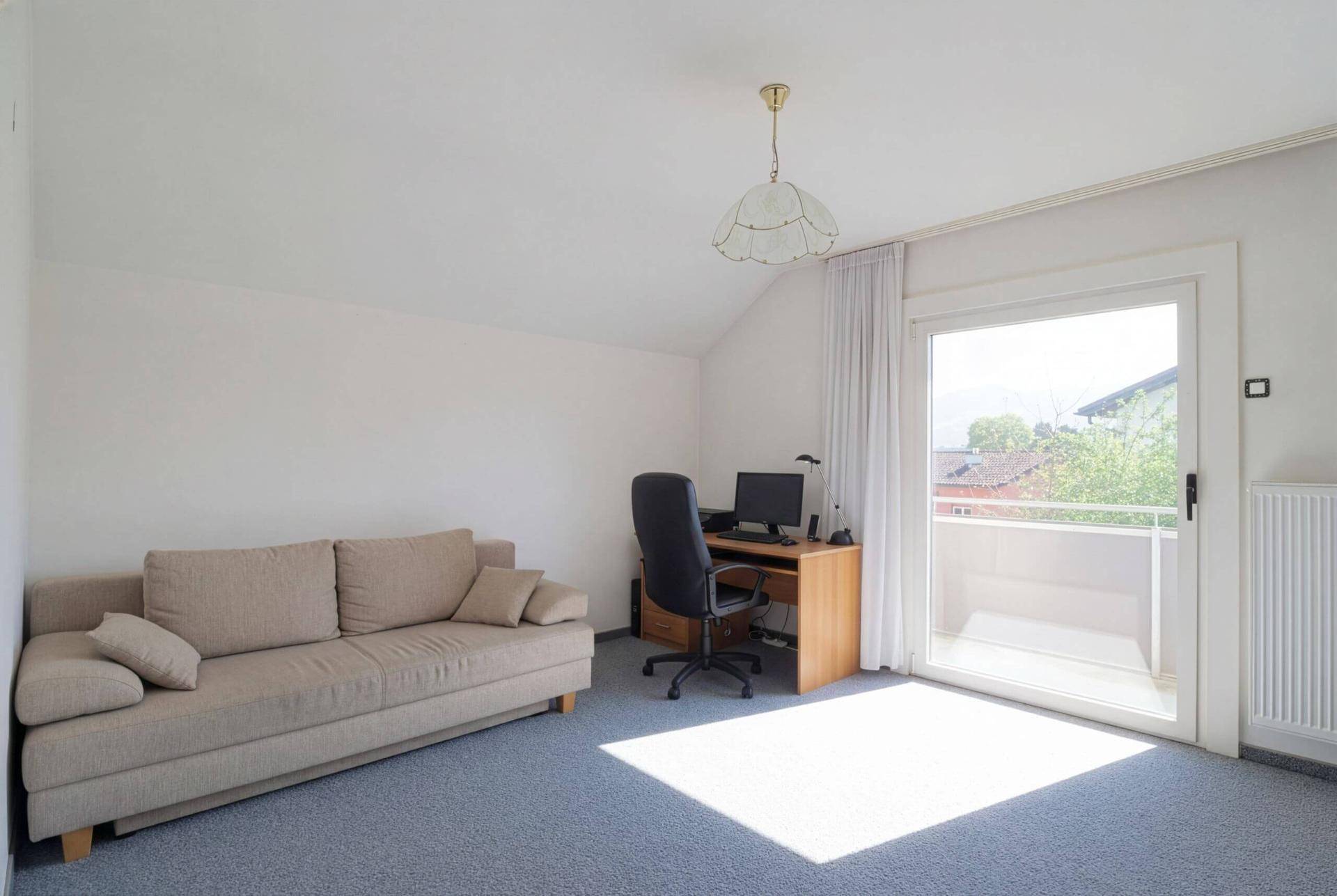 Arbeitszimmer mit Schreibtisch, Sofa und Balkonzugang, ideal für Home-Office oder Gäste.