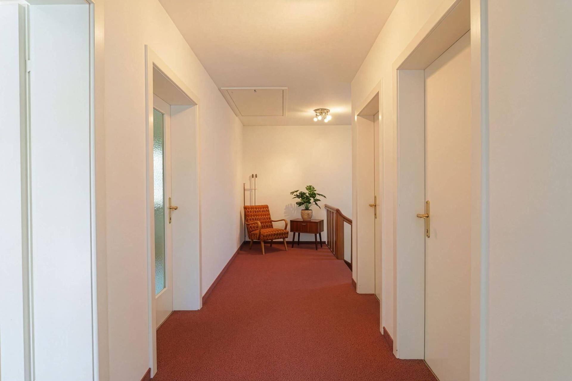 Obergeschoss-Flur mit rotem Teppichboden und Zugang zu weiteren Räumen, hell und geräumig.