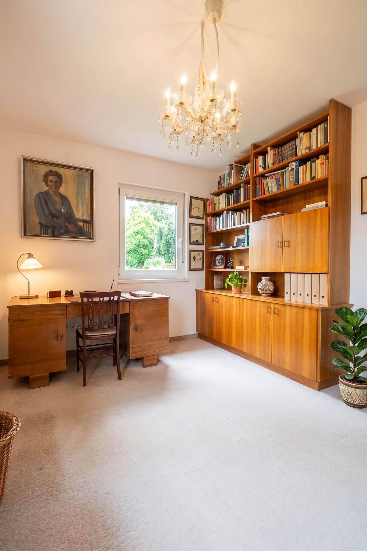 Arbeitszimmer mit Holzmöbeln, Bücherregal und Kronleuchter.