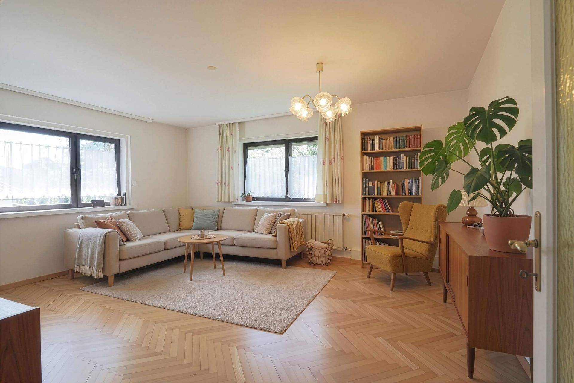 Geräumiges Wohnzimmer mit Parkettboden, beigem Ecksofa und Bücherregal, einladend gestaltet.