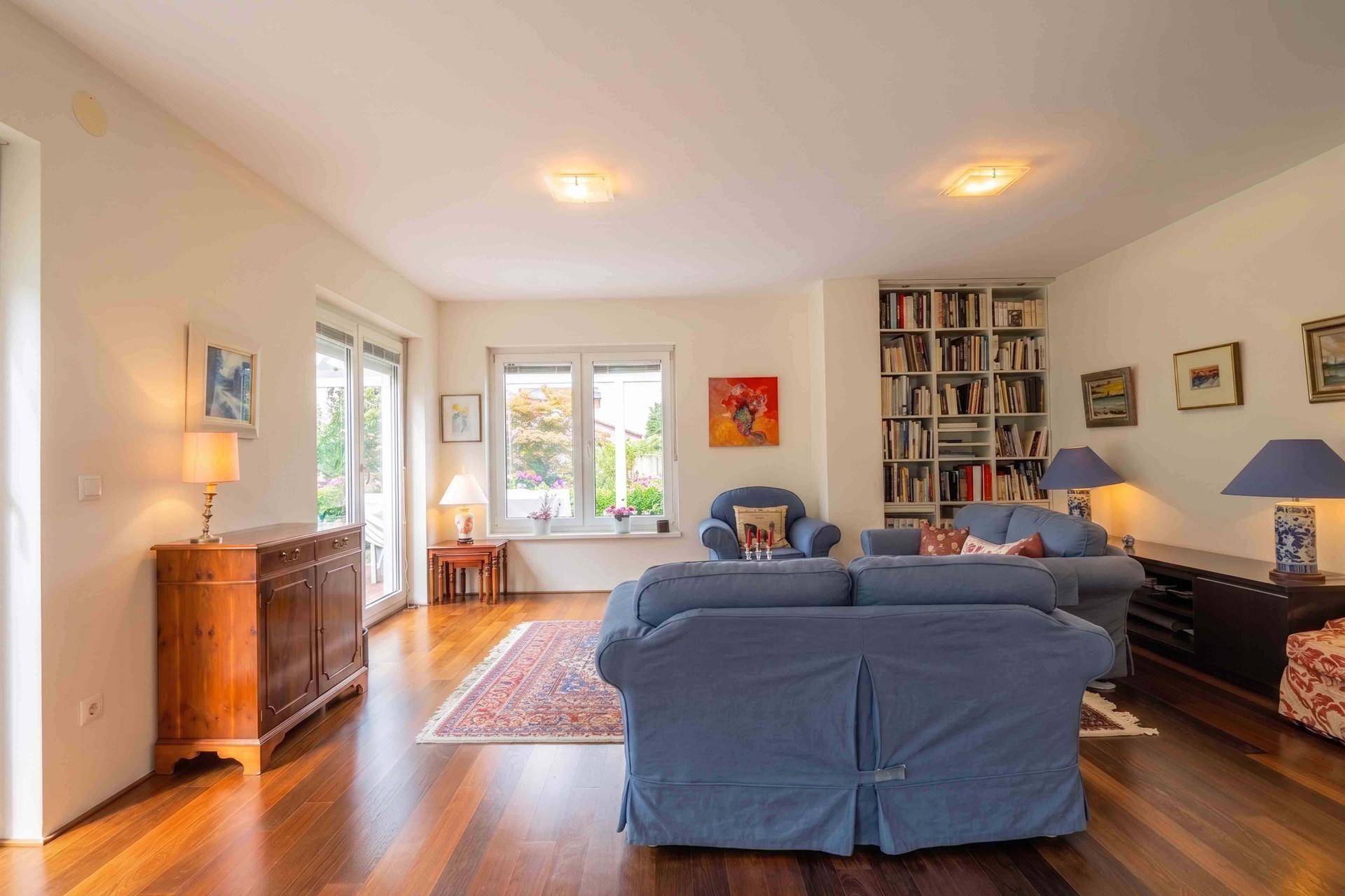 Gemütliches Wohnzimmer mit Parkettboden, blauen Sofas und Bücherregalen.