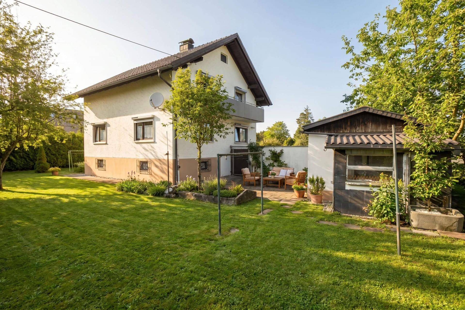 Großzügiger Garten mit Rasenfläche, Terrasse und Gartenhaus, sonnig und gepflegt.