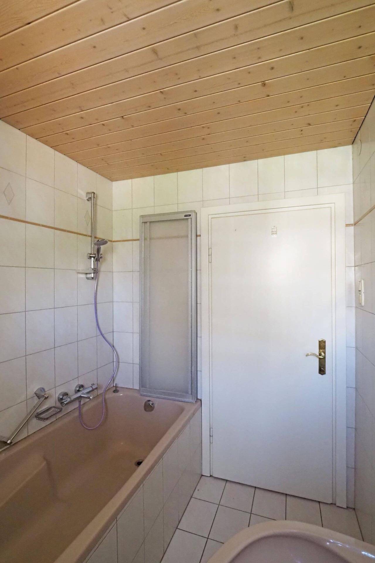 Badezimmer mit Badewanne, Duschabtrennung und Holzdecke, klassisch und gepflegt.