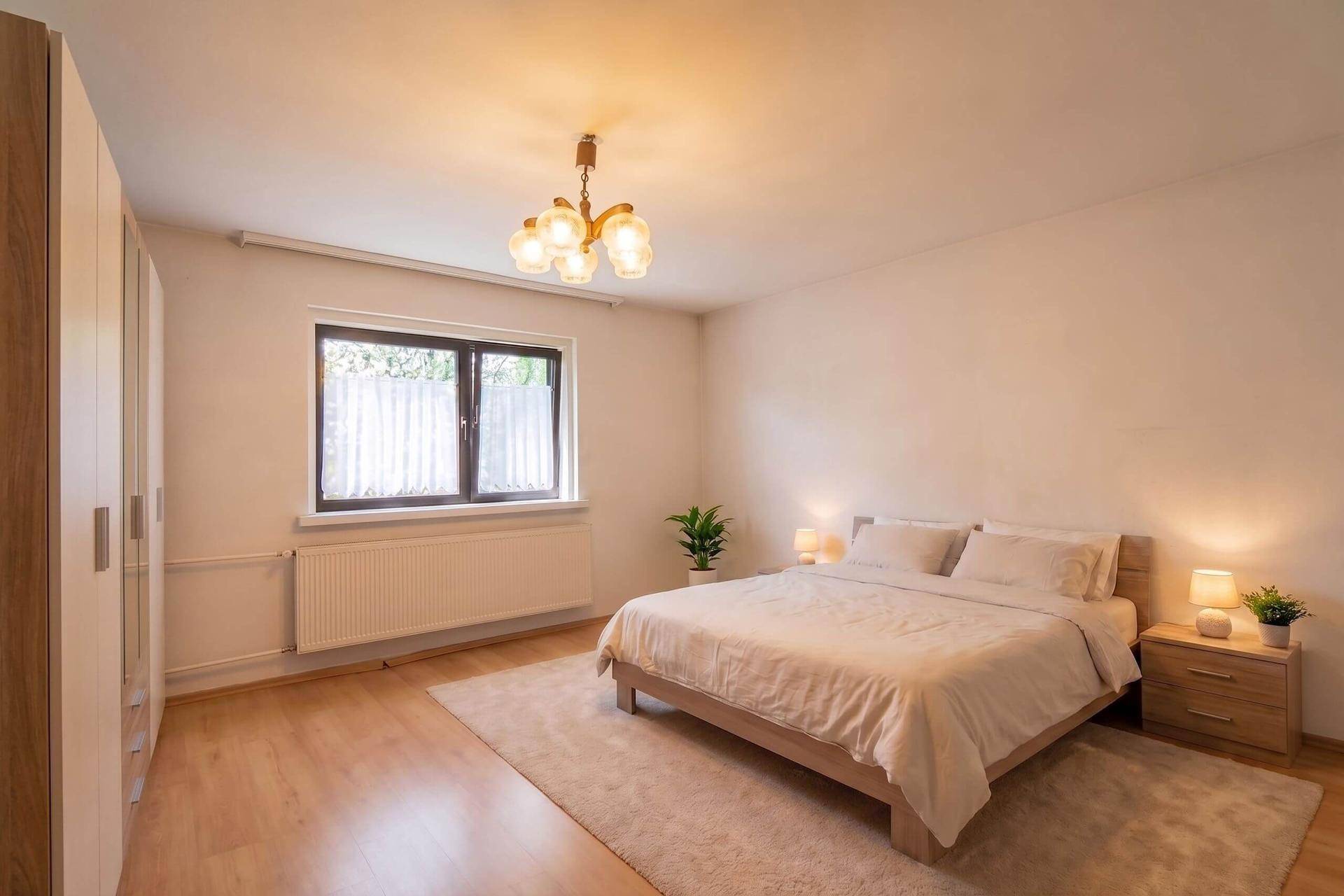 Helles Schlafzimmer mit Doppelbett, Nachttischen und großem Fenster, ruhig und komfortabel.