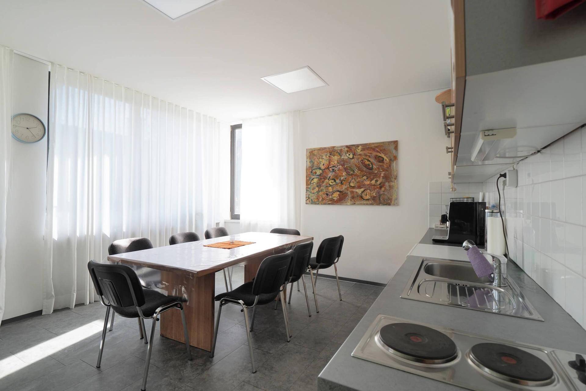 Funktionale Küche mit Essbereich, Spüle und Kochplatten, ideal für Pausen und Mahlzeiten im Büro.