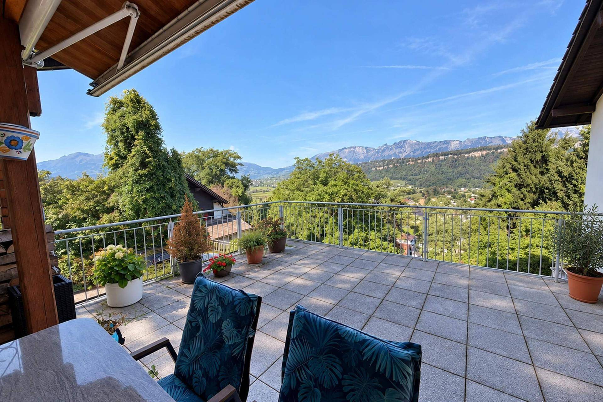 Große Terrasse mit Fliesenboden, Sitzgelegenheiten und weitem Blick auf die umliegende Berglandschaft.