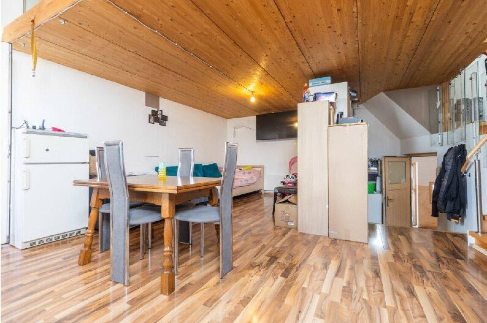 Offener Wohn- und Essbereich mit Holzbalkendecke und Laminatboden, bietet vielseitige Nutzungsmöglichkeiten.