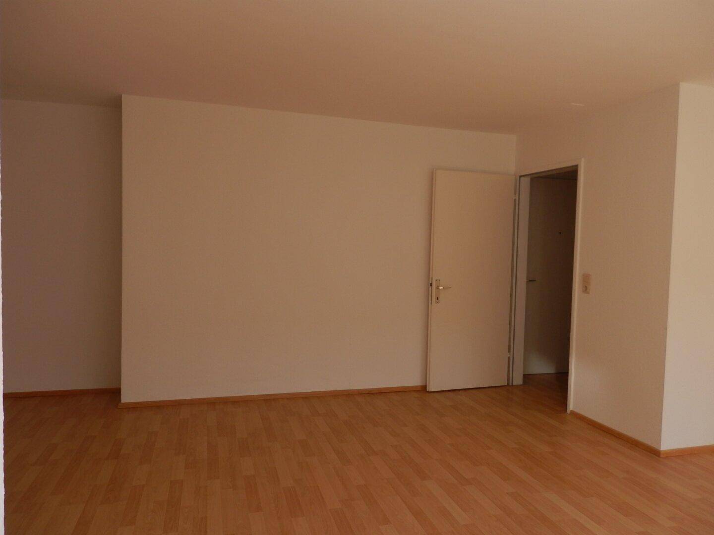 Leeres Wohnzimmer mit Laminatboden und weiß gestrichenen Wänden, ideal für neue Einrichtungsideen.