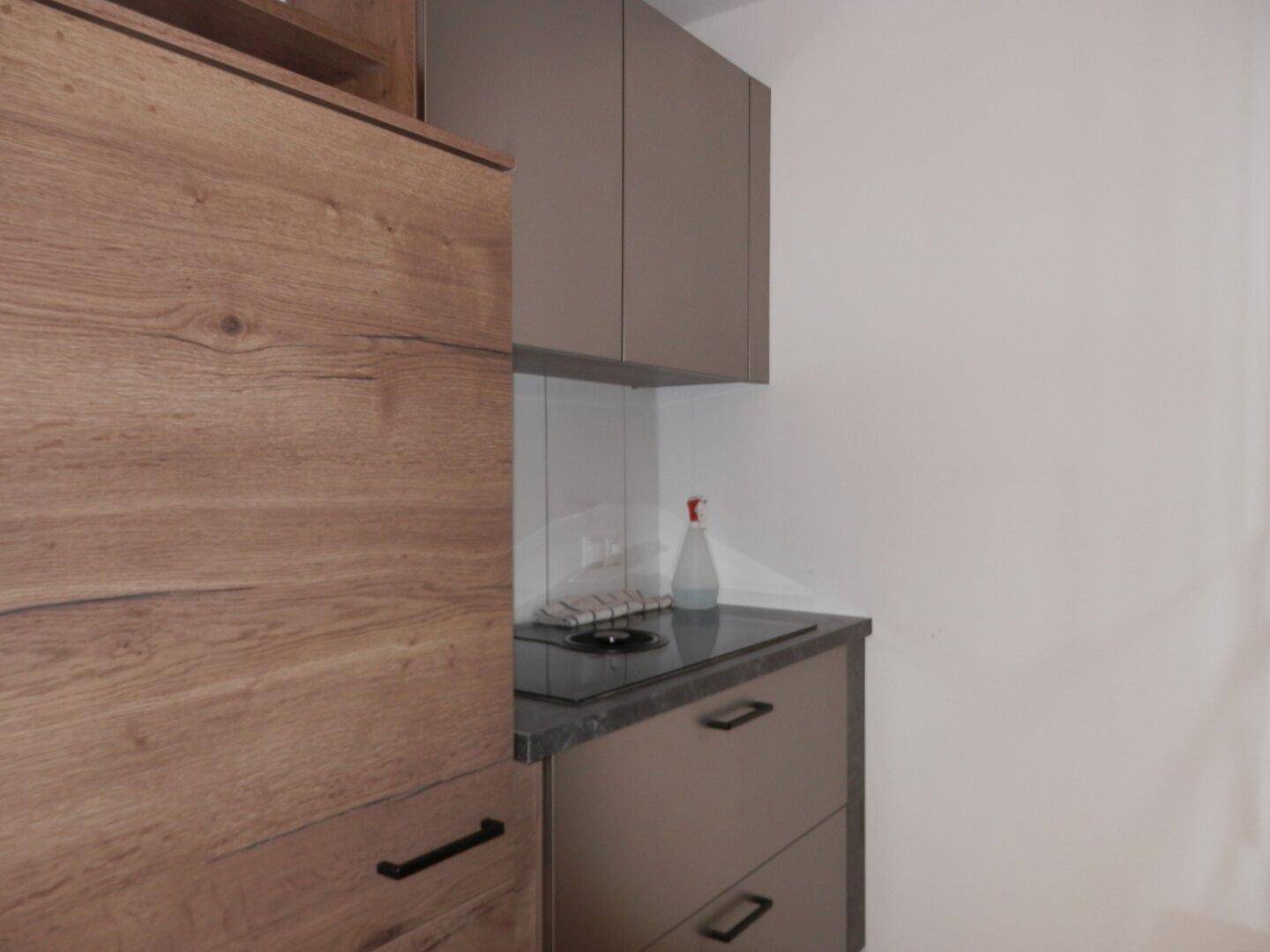 Detailansicht der Küche mit Induktionskochfeld und modernen Holzoptik-Oberschränken.