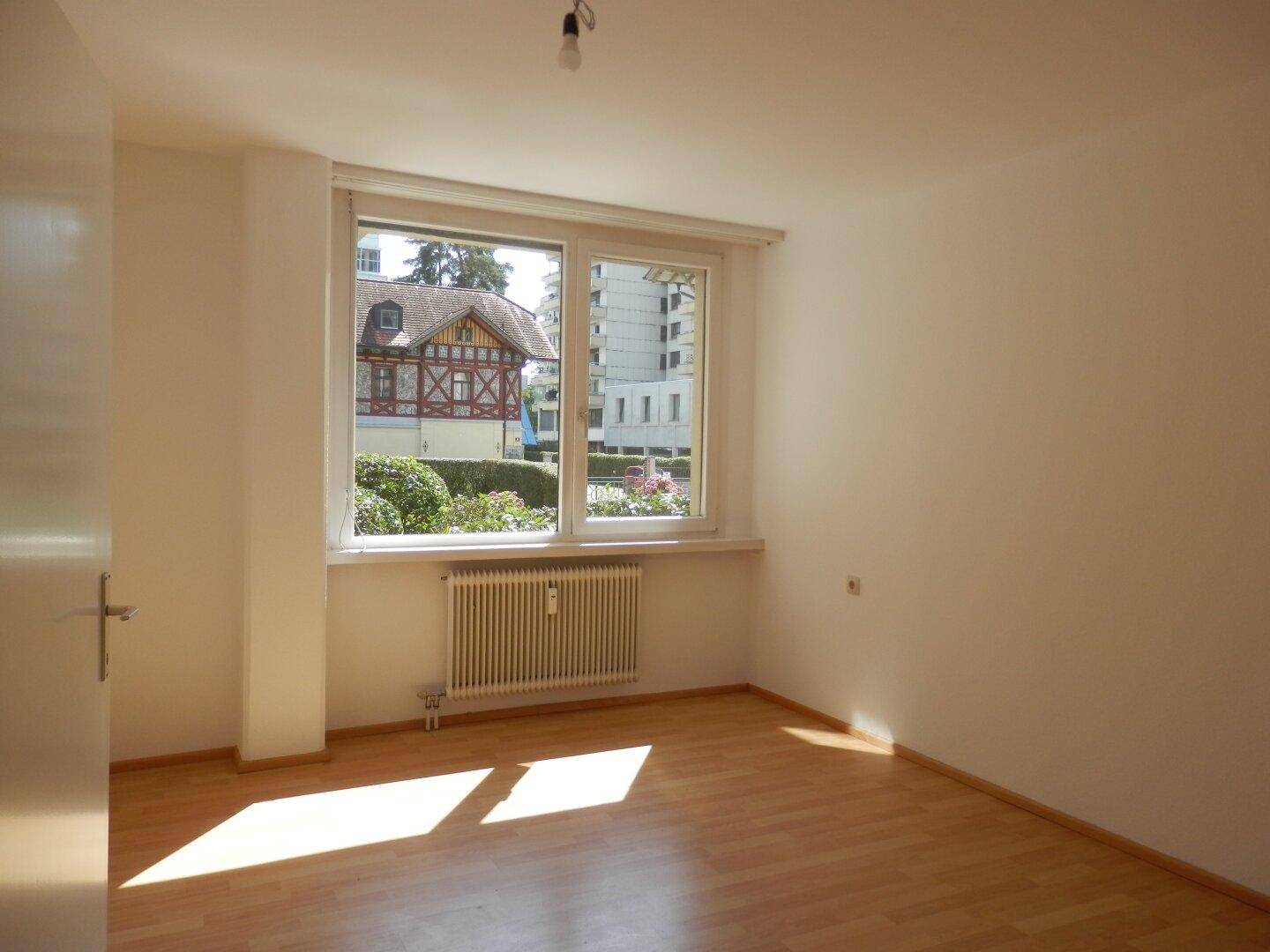 Lichtdurchflutetes Schlafzimmer mit Laminatboden und Fenster mit Blick auf die Umgebung.