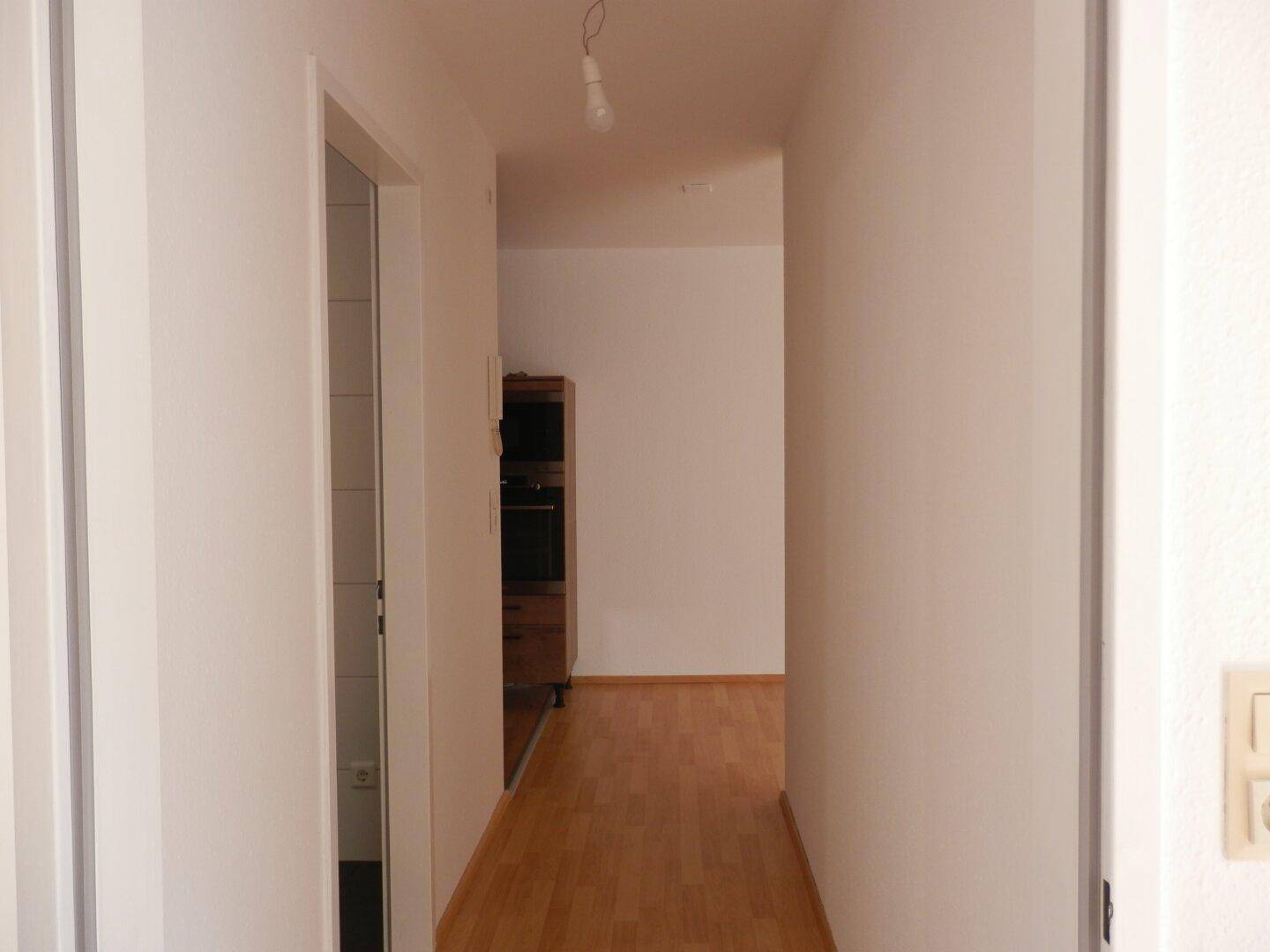 Langer, heller Flur mit Laminatboden, der zu den verschiedenen Räumen der Wohnung führt.