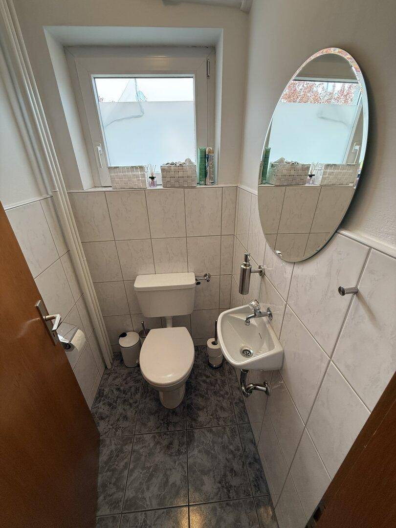 Kleines Gäste-WC mit Fenster, Toilette und Handwaschbecken.