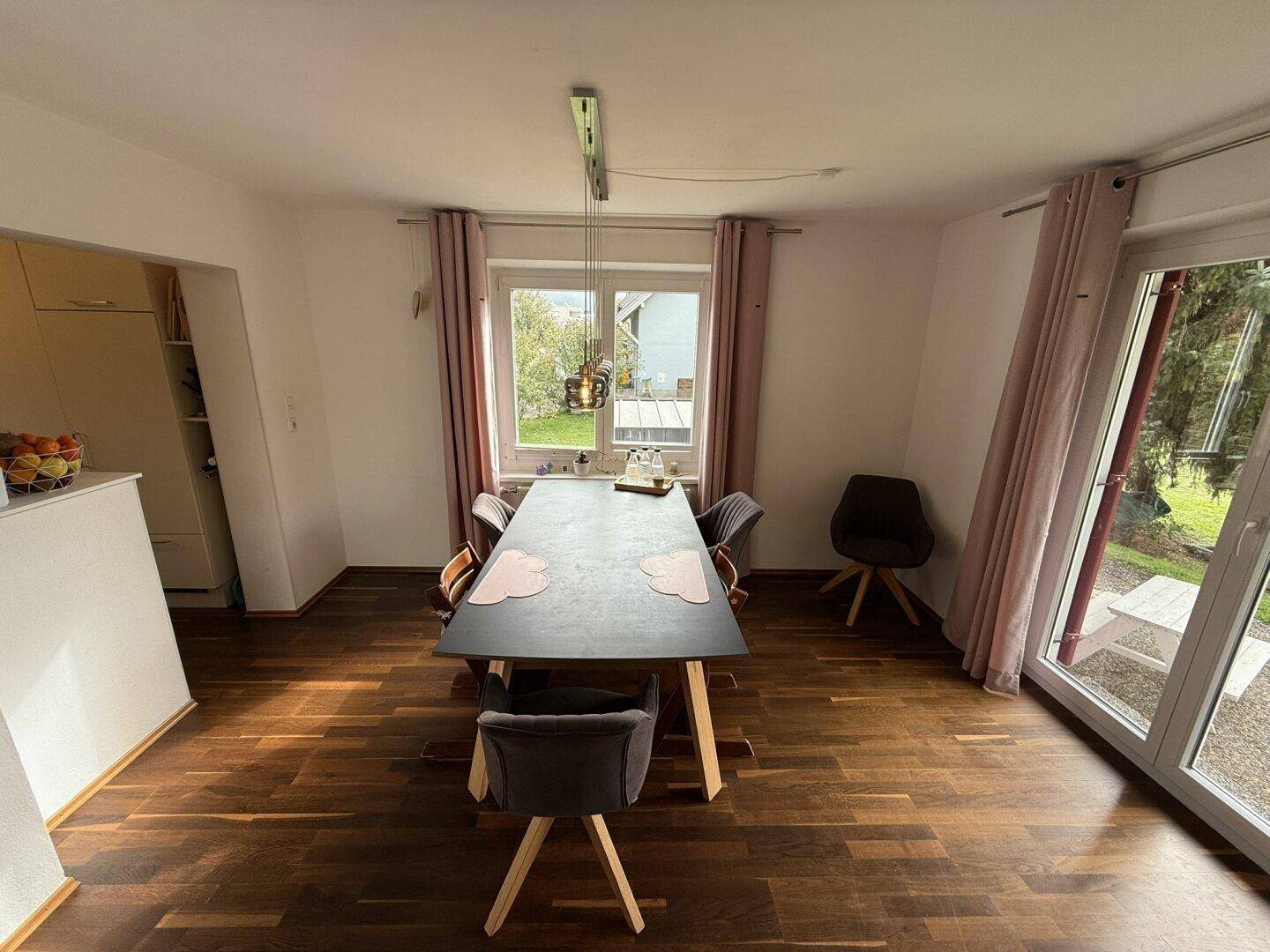Heller Essbereich mit Holzboden, großem Esstisch und direktem Zugang zum Garten.