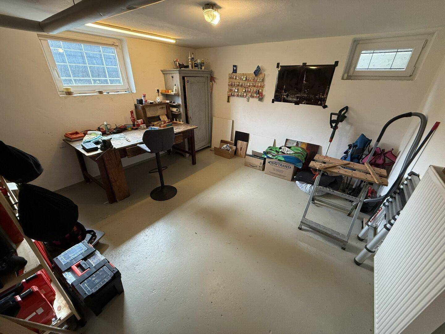 Kellerraum als Werkstatt und Abstellraum genutzt, mit Fenstern und Arbeitsbereich.