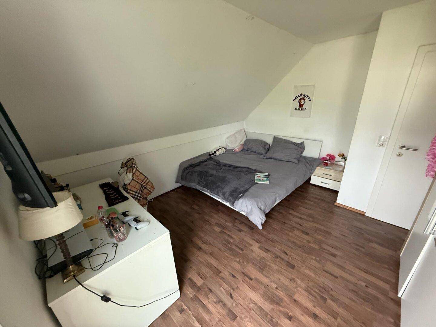 Gemütliches Schlafzimmer mit Bett und Schreibtisch unter der Dachschräge.