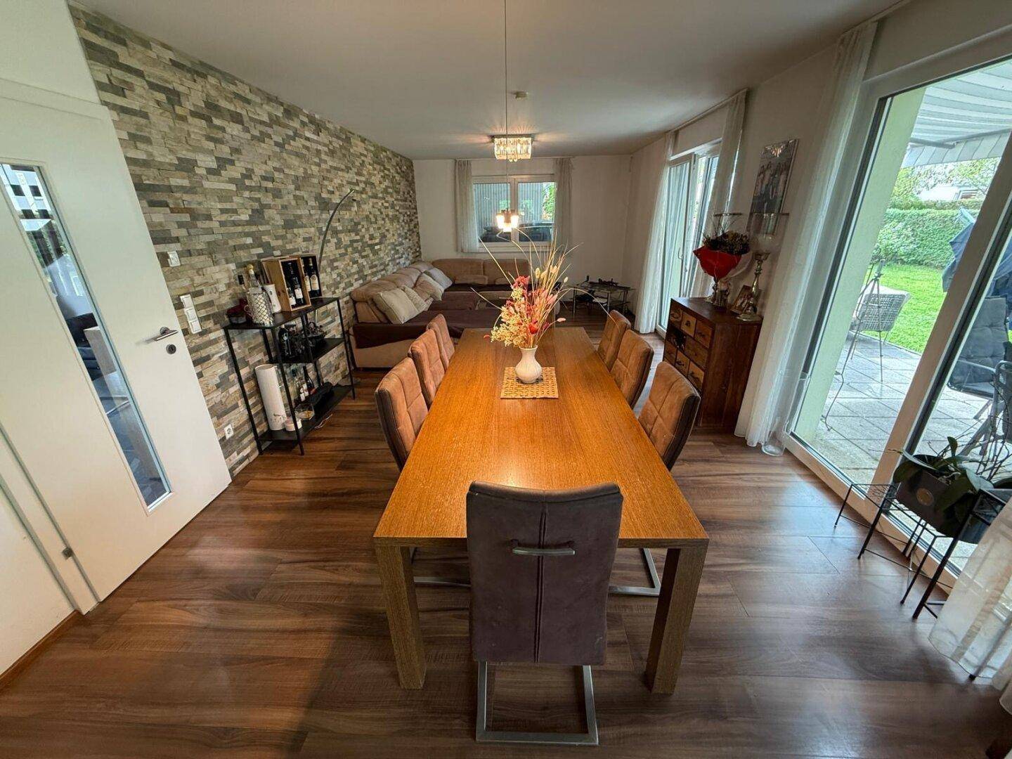 Heller Essbereich mit großem Holztisch, bequemen Stühlen und direktem Terrassenzugang.