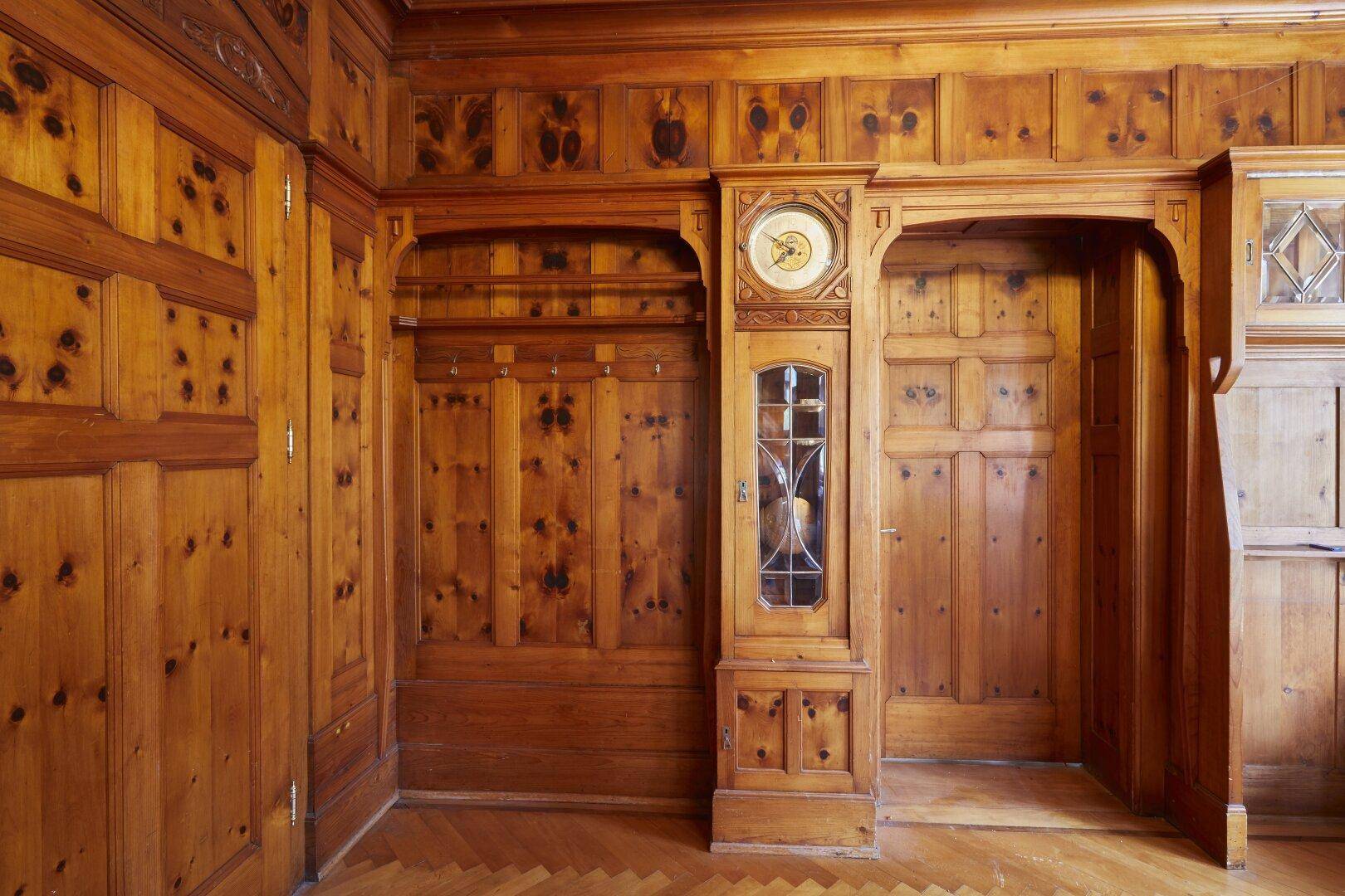Traditioneller Flur mit aufwendiger Holzvertäfelung, Parkettboden und integrierter Standuhr.