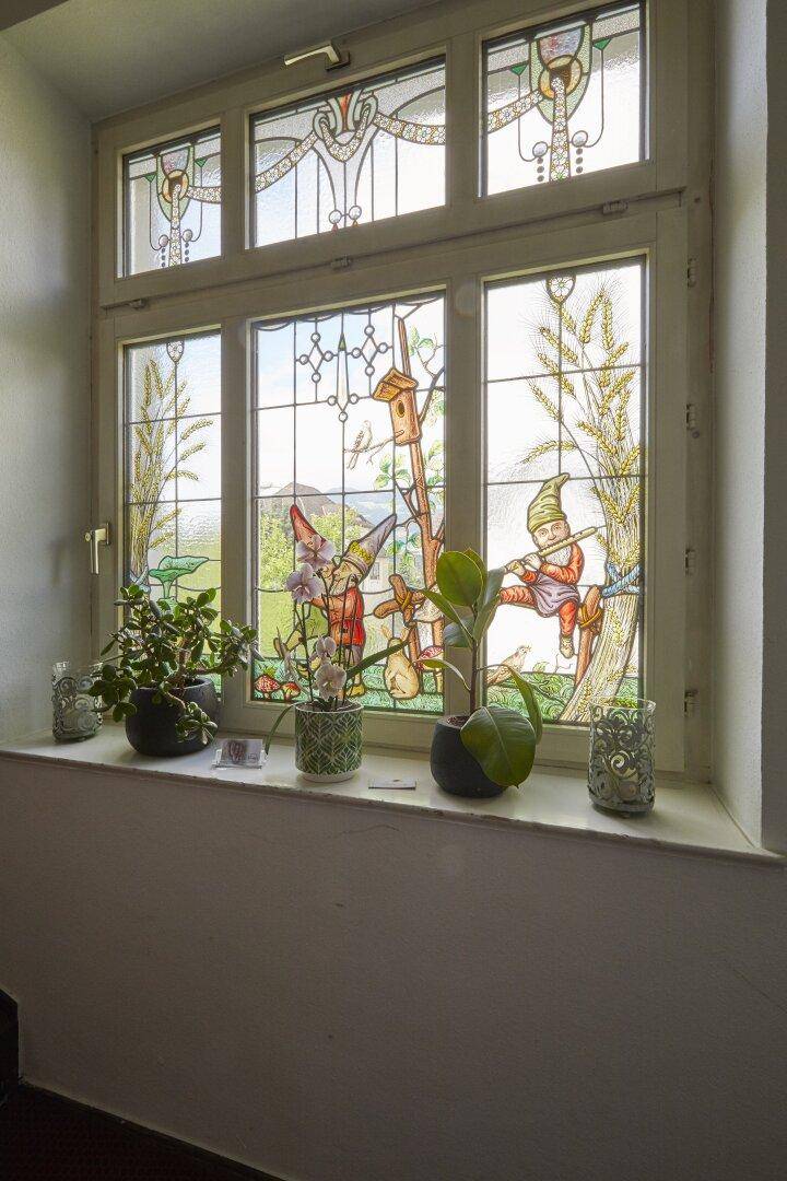 Dekoratives Buntglasfenster mit märchenhaften Motiven, das natürliches Licht hereinlässt.