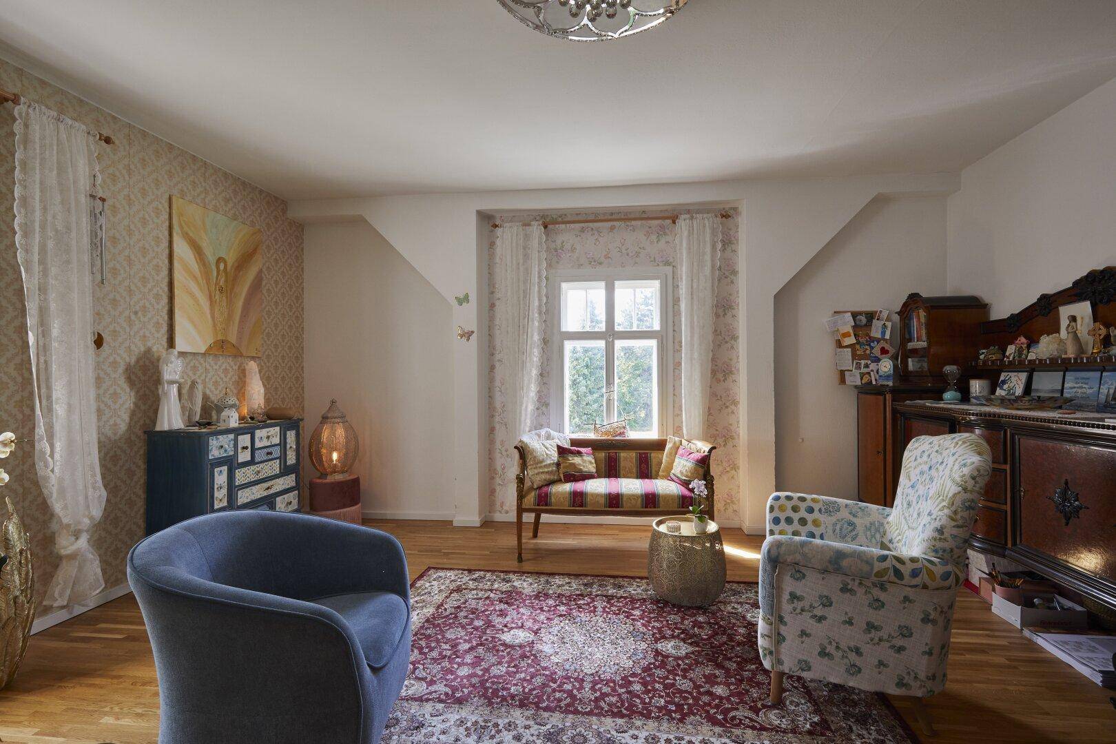 Gemütliches Wohnzimmer mit Parkettboden, dekorativer Tapete und traditionellen Möbeln.