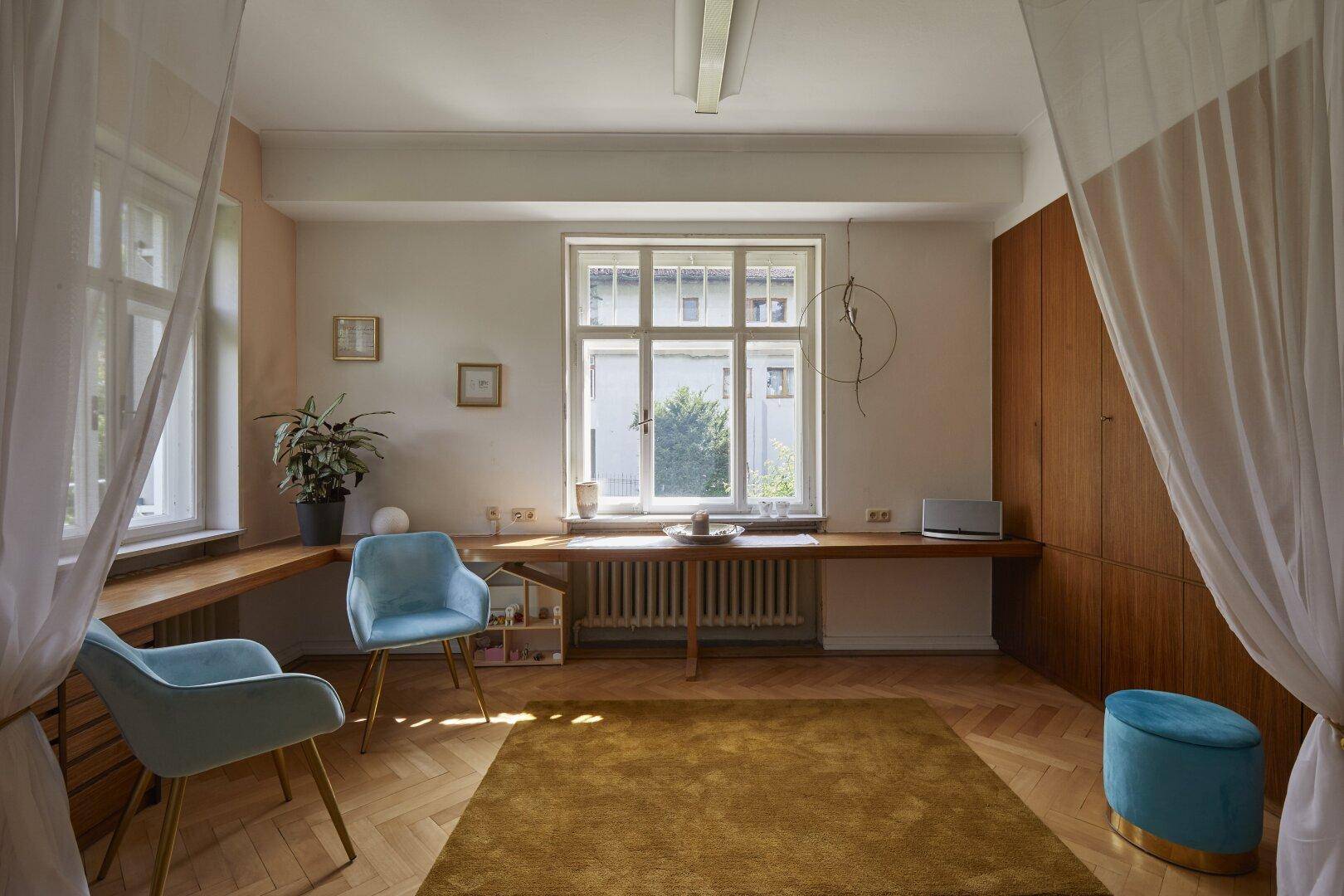 Geräumiges Zimmer mit Parkettboden, großen Fenstern und integrierten Holzschränken.
