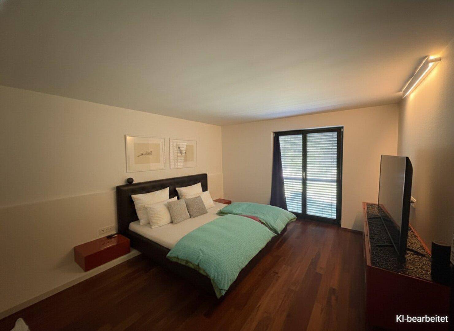Schlafzimmer mit Doppelbett, dunklem Holzboden und großem Fenster mit dunklen Jalousien.