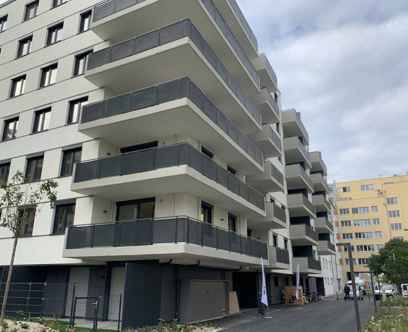 Ansicht eines modernen Mehrfamilienhauses mit gestaffelten Balkonen und zeitgenössischer Architektur.