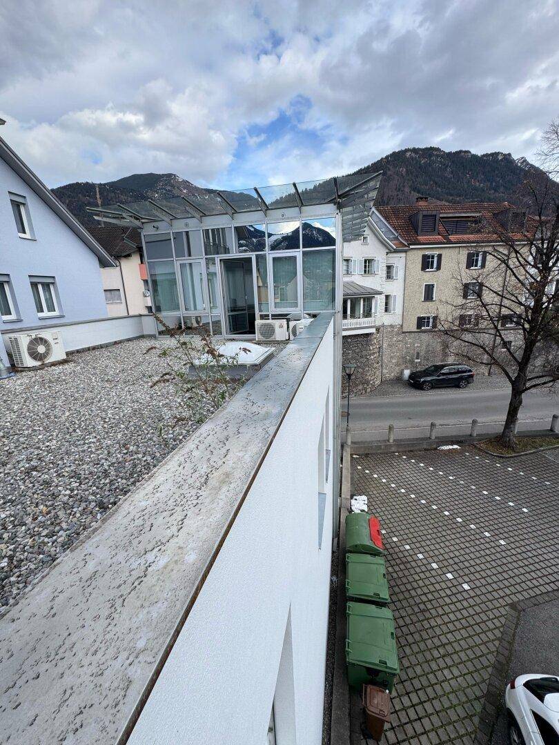 Blick von einer oberen Ebene auf die Glasfassade des Gebäudes und die umliegende Berglandschaft.