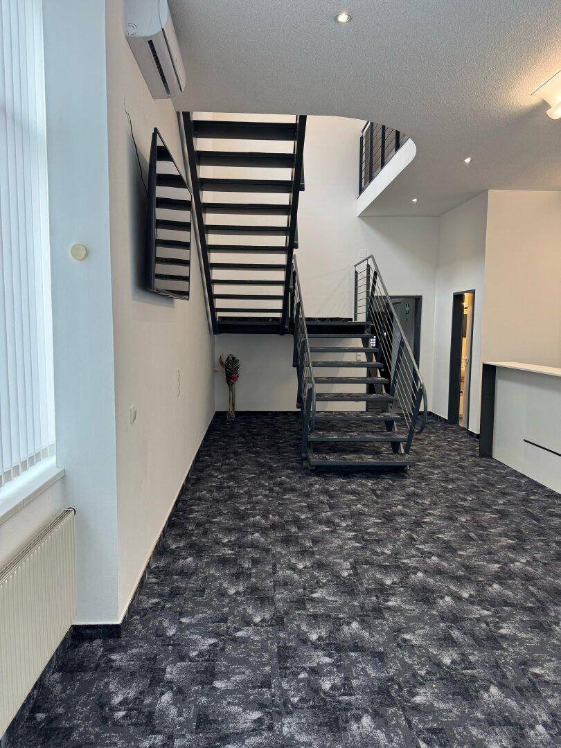 Eingangsbereich mit offener Treppe, Teppichboden und moderner Beleuchtung.