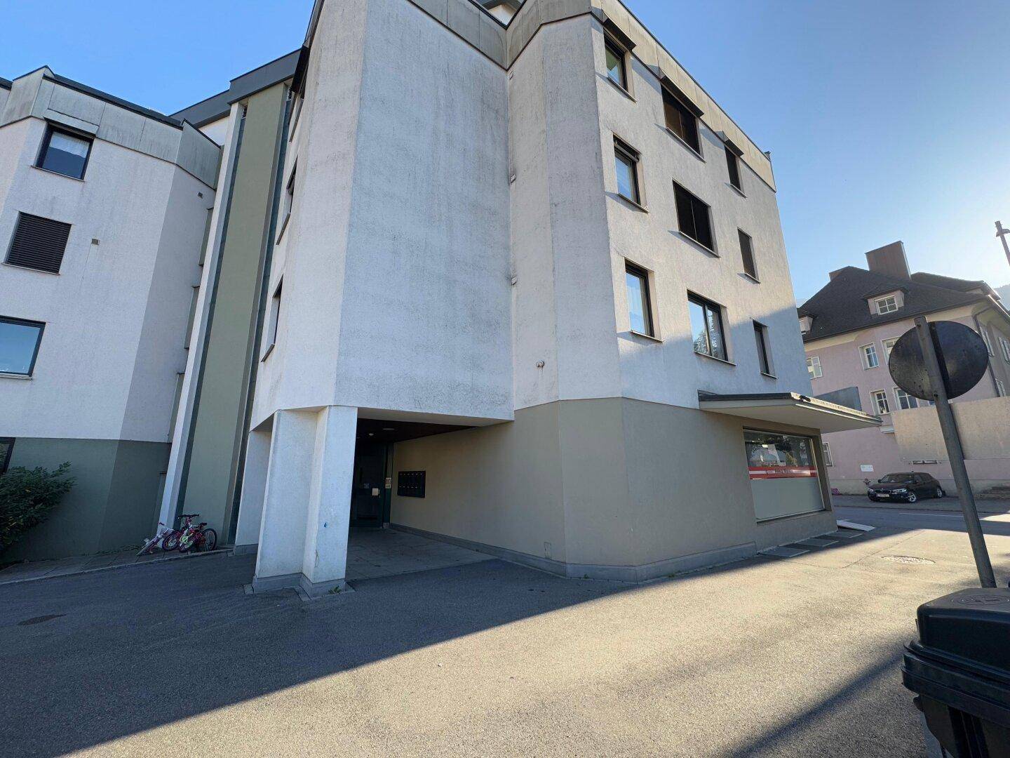 Mehrstöckiges Wohngebäude mit heller Fassade und mehreren Fenstern unter blauem Himmel.