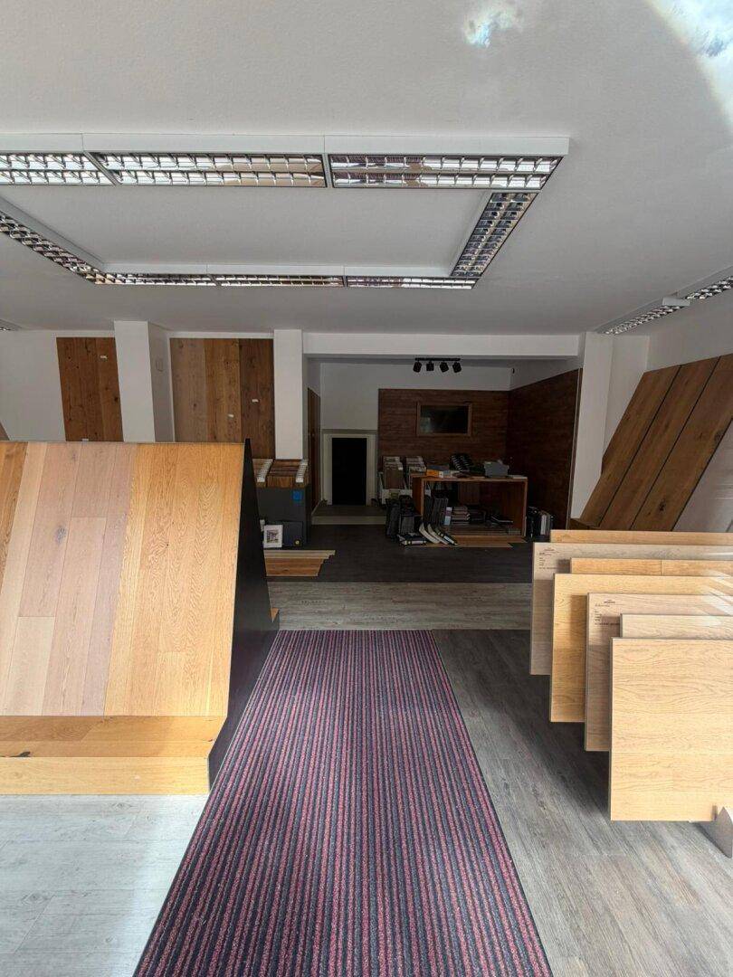 Innenansicht eines Ausstellungsraums mit verschiedenen Bodenbelagsmustern und Holzverkleidungen.