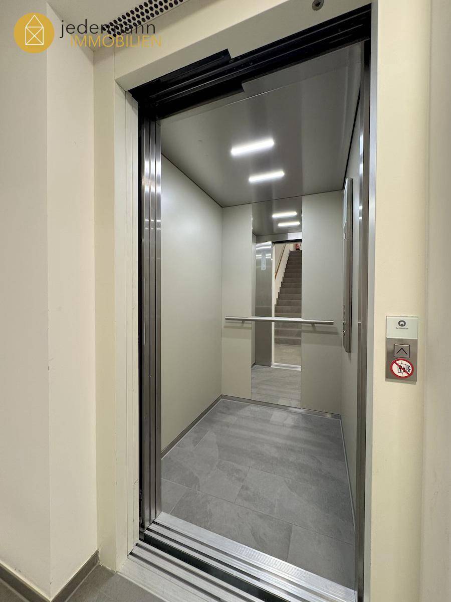 Moderner Aufzug im Gebäude mit Spiegelflächen und hellem Interieur.