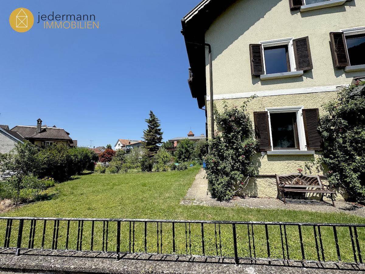 Gartenbereich vor dem Haus mit Rasenfläche, Bepflanzung und einer Sitzbank.