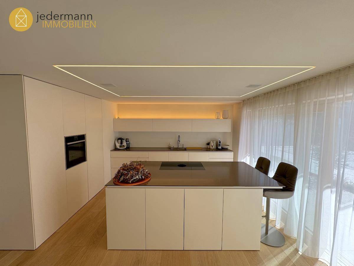 Moderne Einbauküche mit Kochinsel, integrierten Geräten und großen Fenstern.