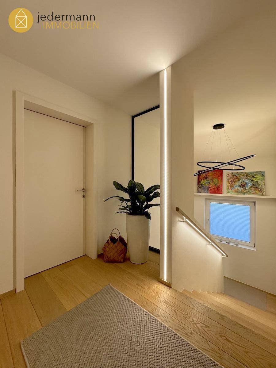 Moderner Flur mit Holztreppe, indirekter Beleuchtung und Holzboden.