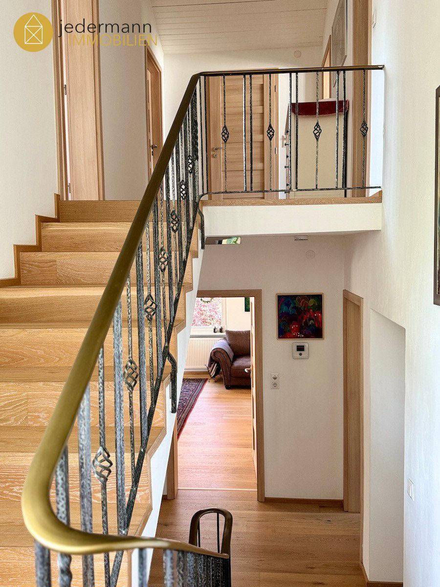 Elegante Holztreppe mit schmiedeeisernem Geländer, die die verschiedenen Ebenen des Hauses verbindet.
