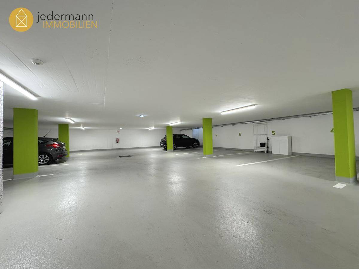 Geräumige Tiefgarage mit markierten Stellplätzen und hellgrünen Säulen.