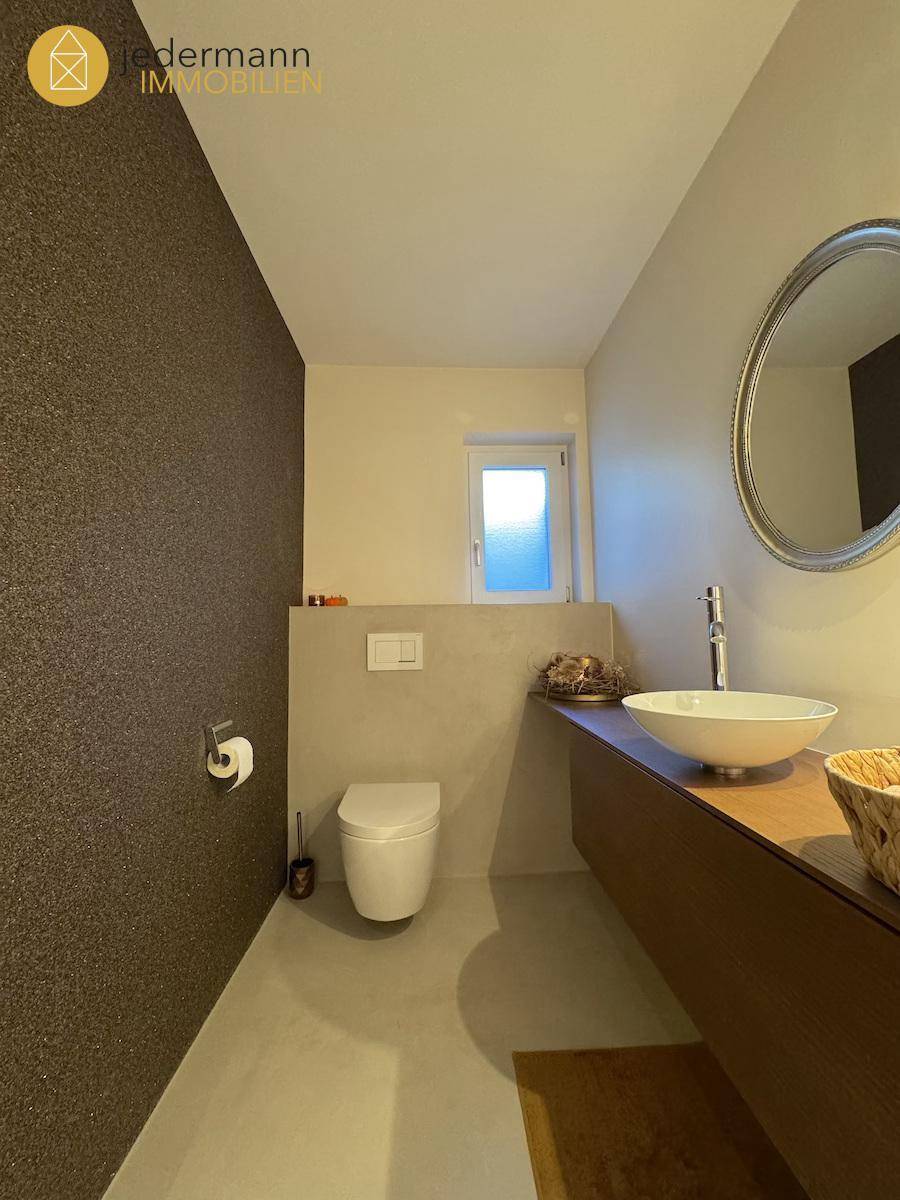 Modernes Gäste-WC mit Wand-WC, Aufsatzwaschbecken und kleinem Fenster.