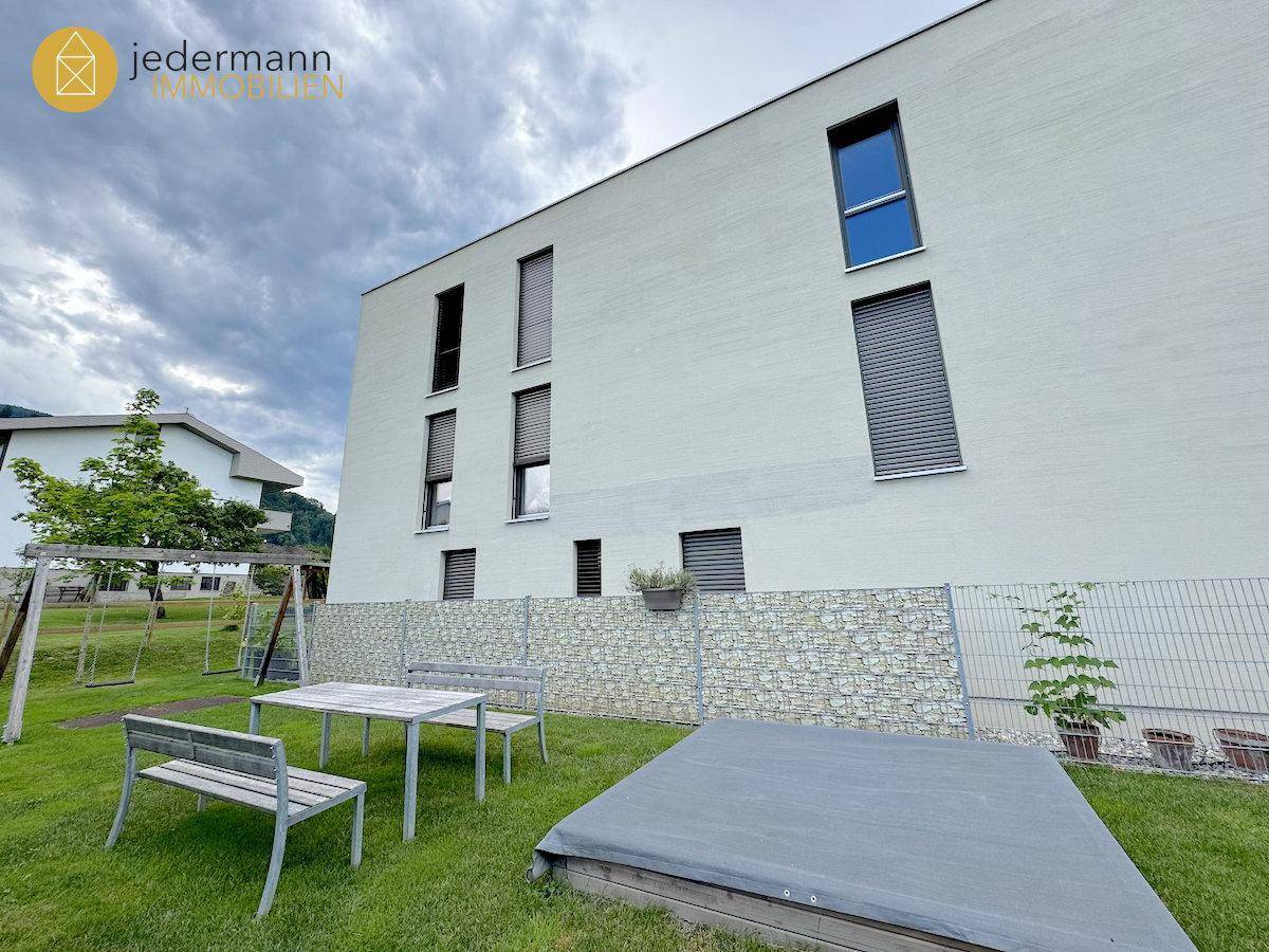 Gemeinschaftlicher Gartenbereich mit Spielplatz und Sitzgelegenheiten hinter dem Gebäude.