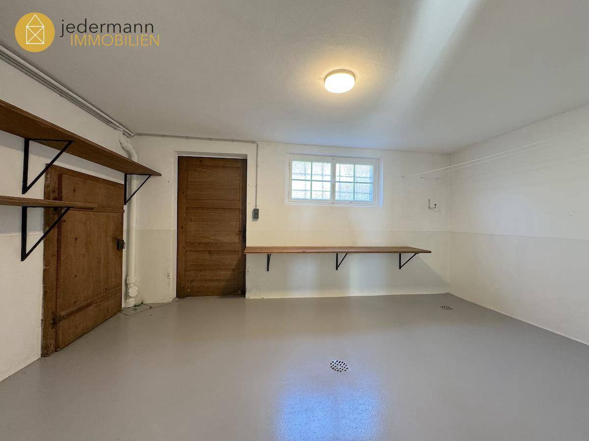 Kellerraum mit Regalen, Holztür und einem kleinen Fenster für Belüftung.