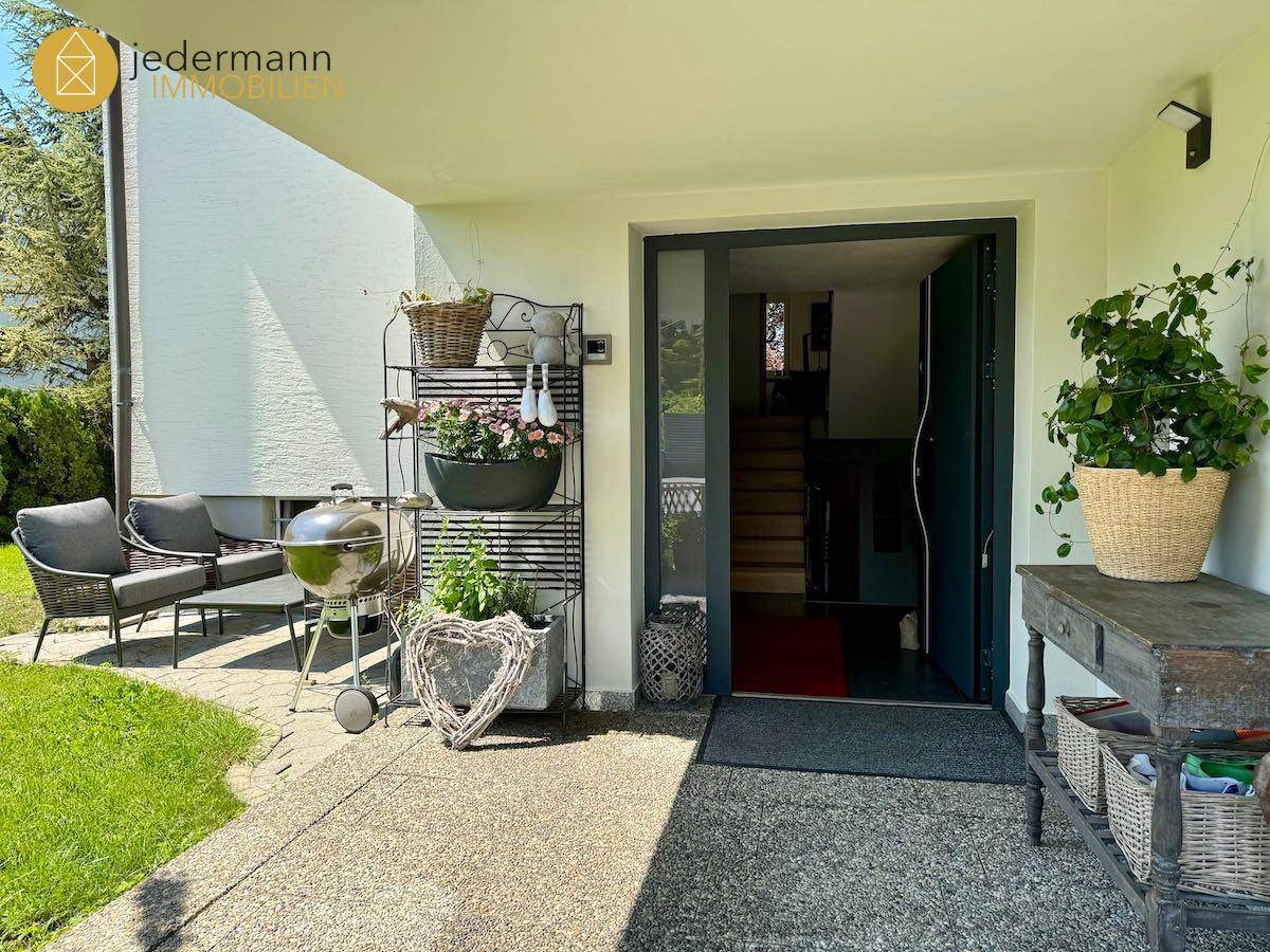Überdachte Terrasse am Eingangsbereich mit Sitzgelegenheiten und Grill.