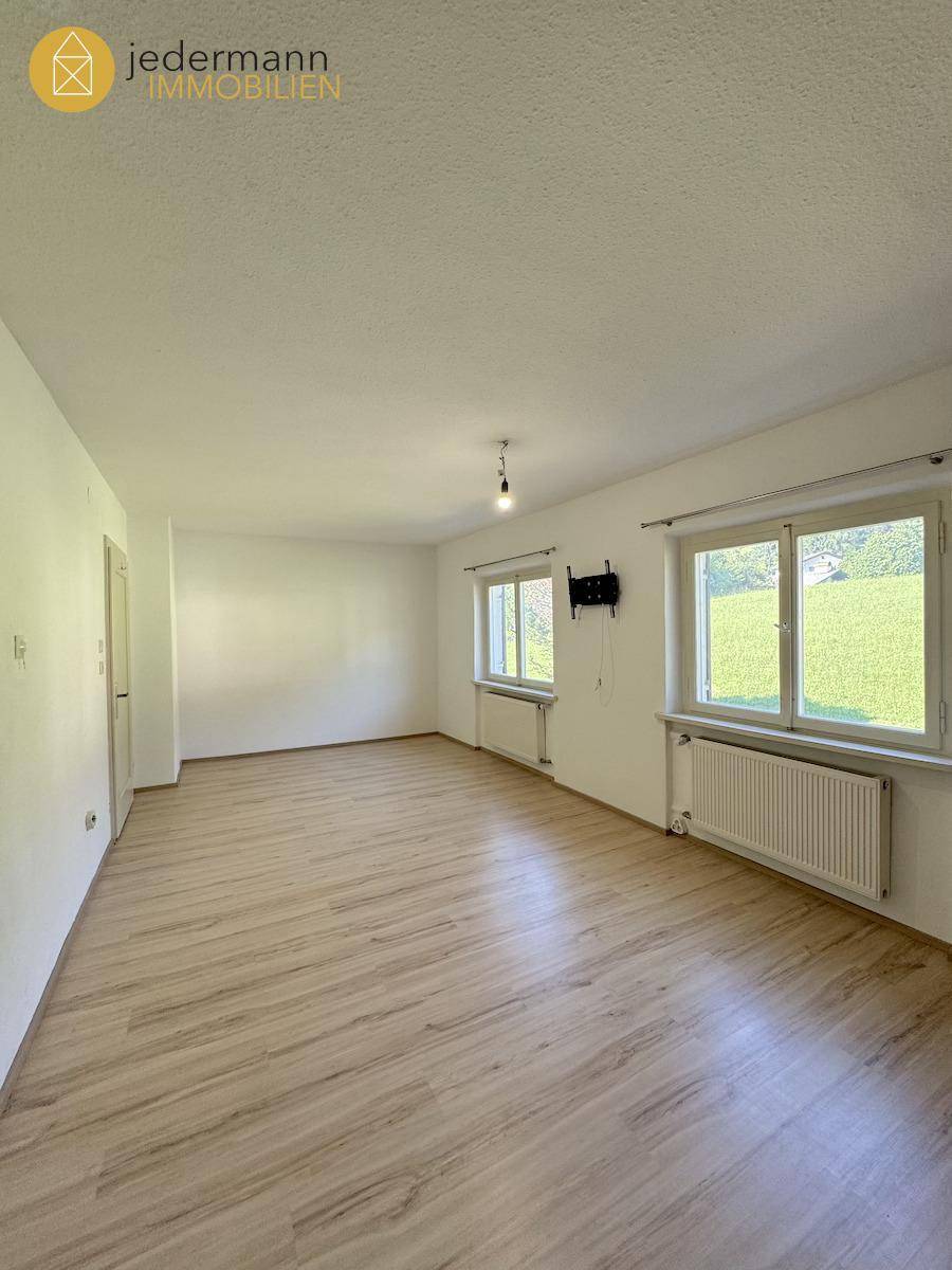 Geräumiges Zimmer mit Laminatboden und Fenstern mit Blick auf die grüne Umgebung.