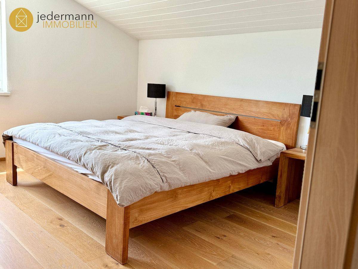 Geräumiges Schlafzimmer mit Holzbett, Nachttischen und hellem Parkettboden.