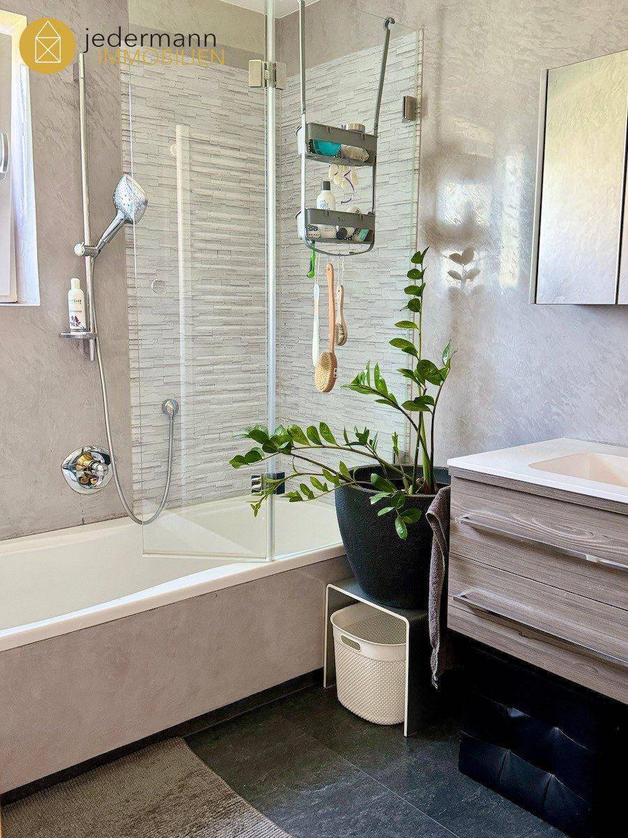Badezimmer mit Badewanne, integrierter Dusche und modernem Waschtisch.