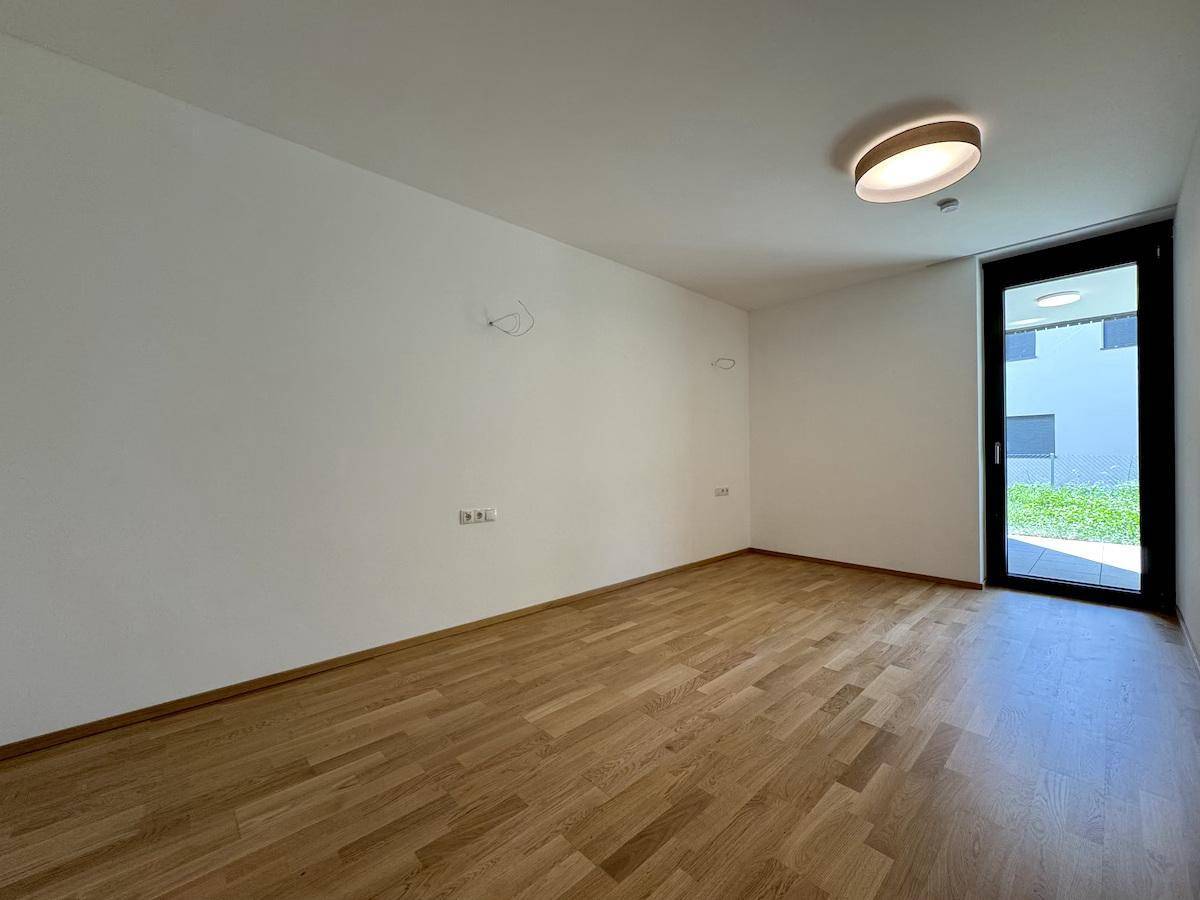Helles Zimmer mit Parkettboden und Zugang zu einem Außenbereich.