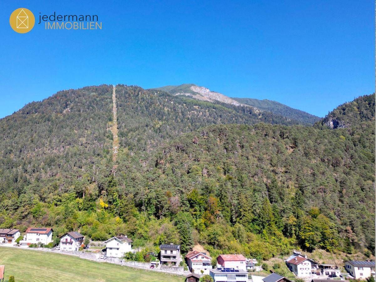 Malerische Berglandschaft mit bewaldeten Hängen und Häusern im Tal.