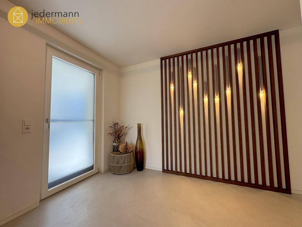 Heller Eingangsbereich mit dekorativer Holzlamellenwand und indirekter Beleuchtung.