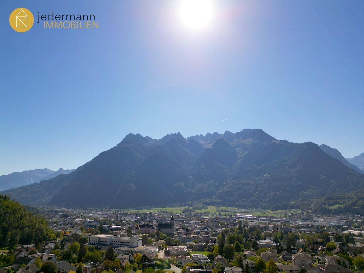 Panoramablick auf die Stadt und die imposante Bergkette unter strahlend blauem Himmel.